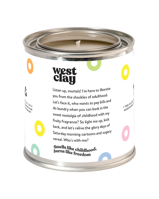 A West Clay candle in a silver metal tin with a white label featuring colorful circular accents and black text, shown on a plain white background.