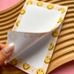 Notepad with smiley face design on a wooden surface