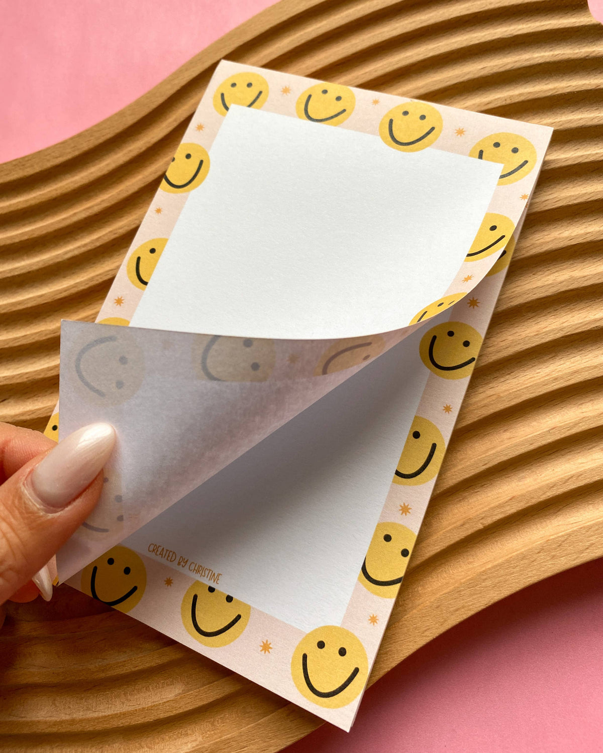 Notepad with smiley face design on a wooden surface