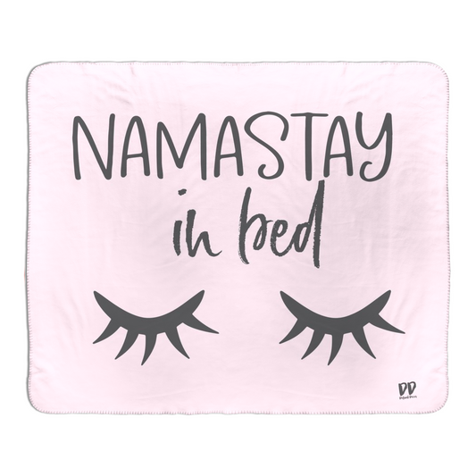 Pink Fleece Sherpa Blanket with Gray text that reads "Namastay in bed" with a set of closed eyelash eyes.